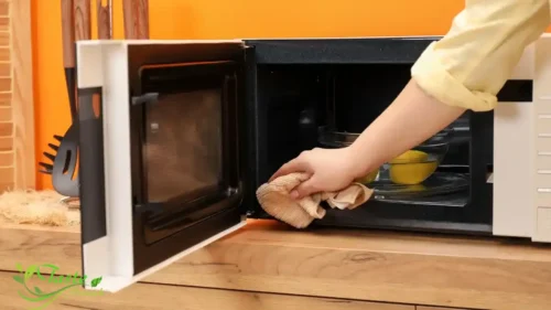 "Clean microwave with lemon steam method showing bowl of lemon water inside microwave"